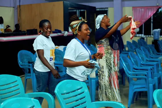 Attendees standing between blue chairs during congregational worship