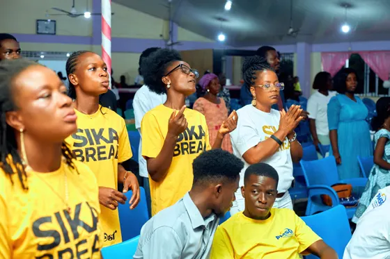 Attendees in yellow shirts singing alongside other members of the congregation
