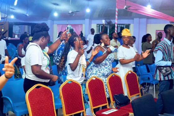 Congregation standing and worshipping between rows of chairs