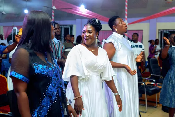 Women in white and blue dresses standing together during worship