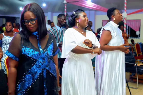 Three women singing together in the congregation