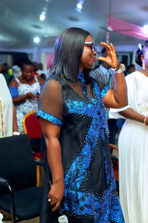 A singer in a blue dress holding a microphone in the congregation