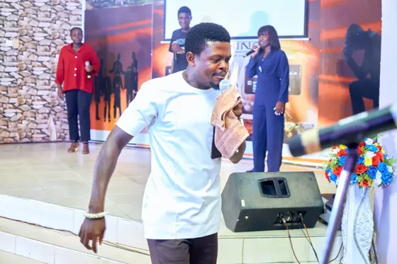 A man holding a microphone at the front of the church stage