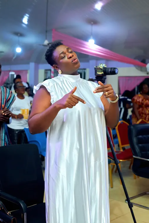 A woman in a white dress worshipping at Tokens of Praise 2025